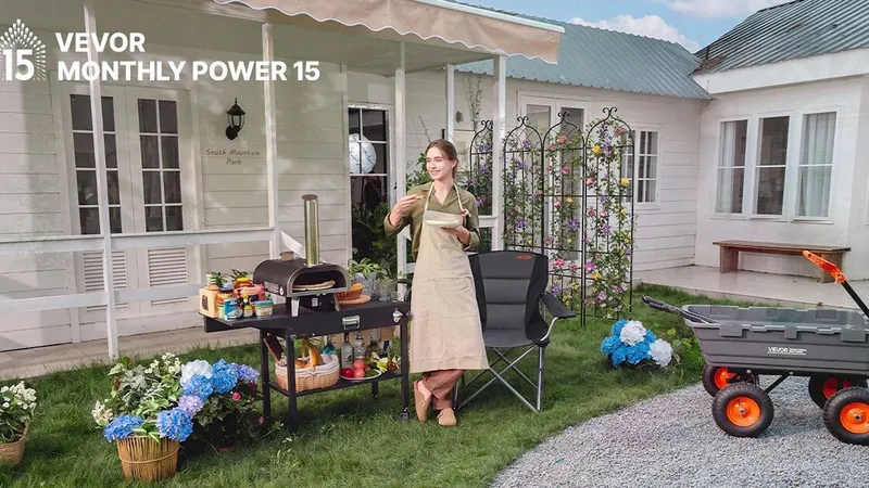 Woman beside an outdoor pizza oven cart and folding chair, with a utility wagon on a lawn.