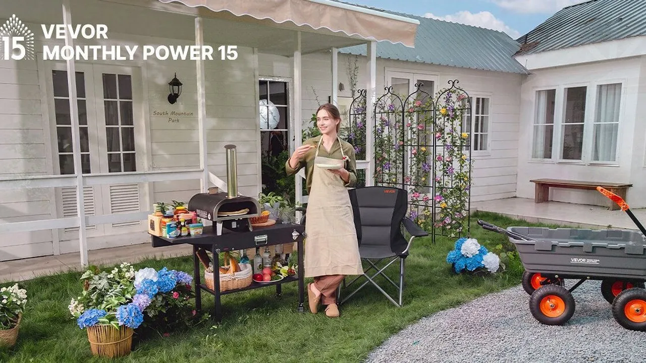 Woman beside an outdoor pizza oven cart and folding chair, with a utility wagon on a lawn.