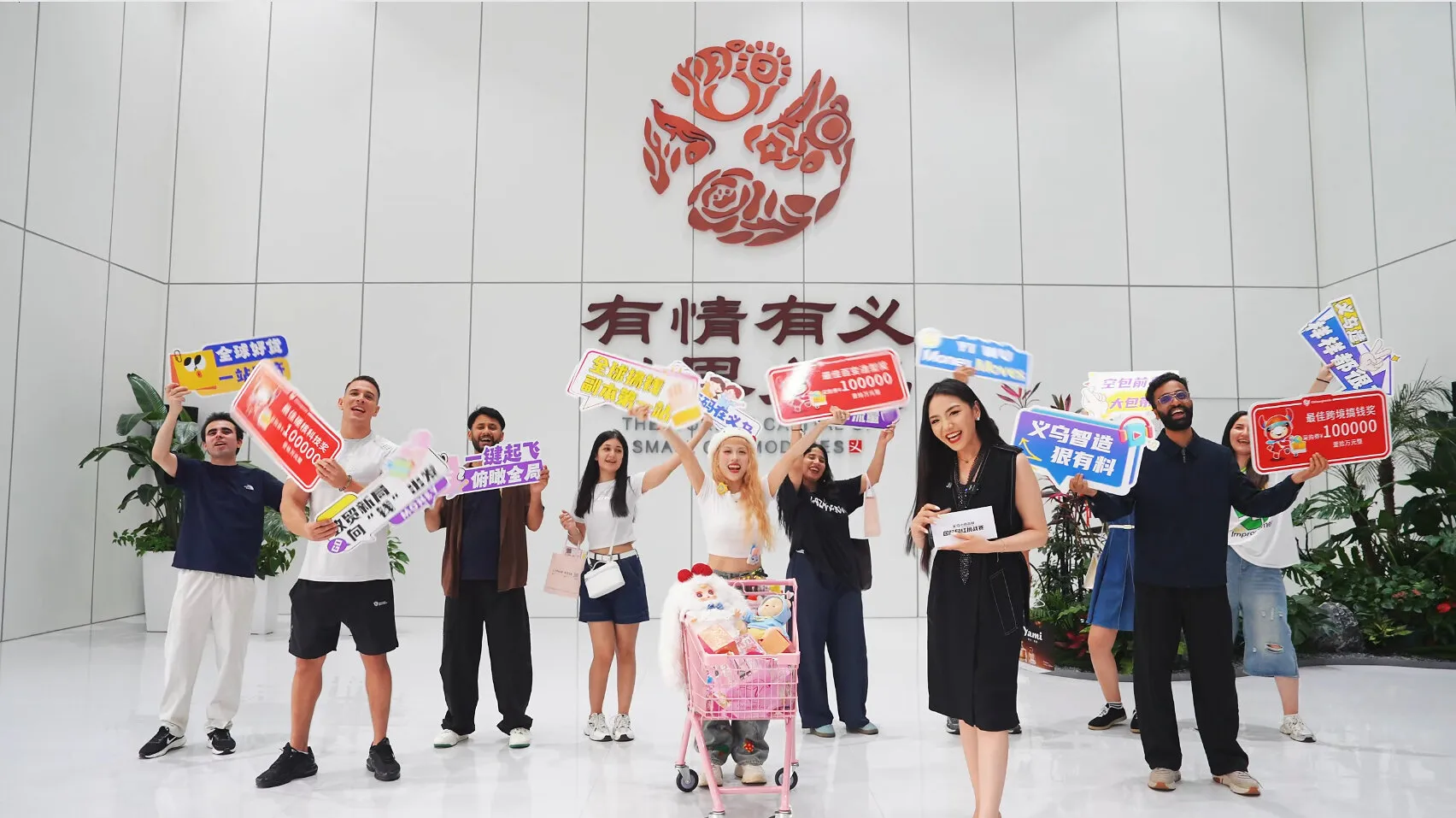A group holds promotional signs beside a pink shopping cart in a lobby with Chinese signage.
