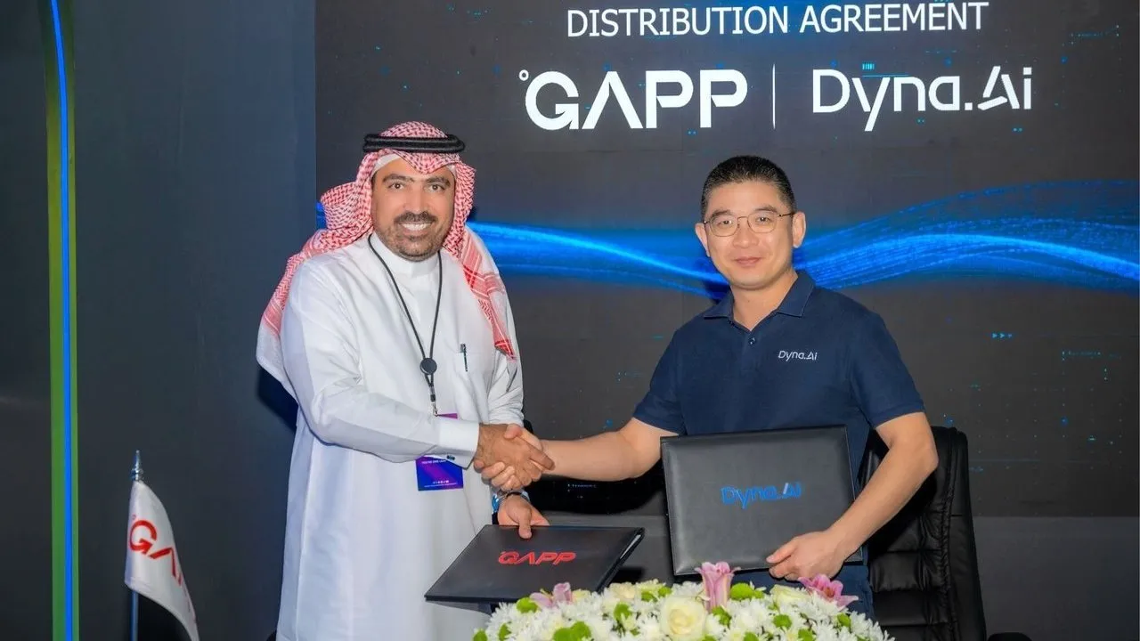 Two men shake hands while holding agreement folders before a GAPP and Dyna.Ai distribution agreement backdrop.
