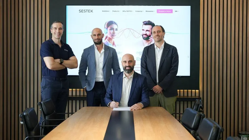 Four men in a boardroom, with one seated signing a document in front of a SESTEK screen.