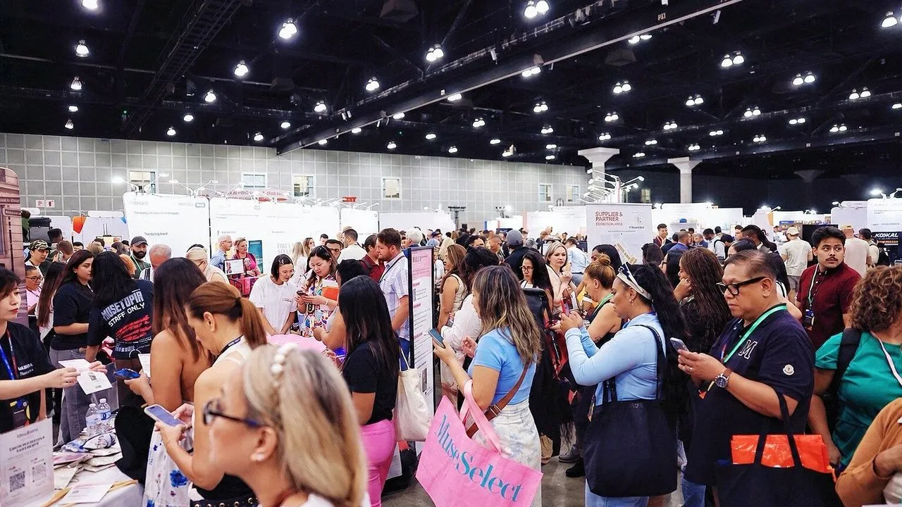 Crowd of attendees browsing booths at a busy indoor trade show.