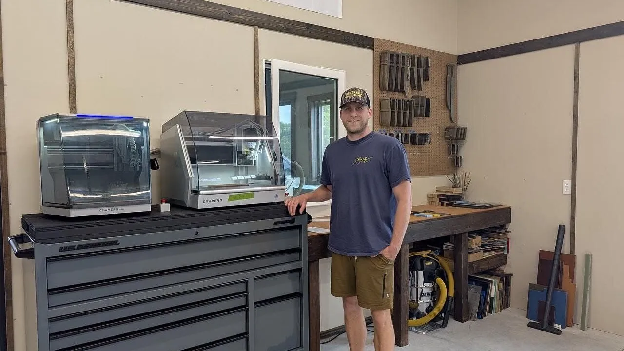 Man standing beside a tool chest with two enclosed machines in a workshop.