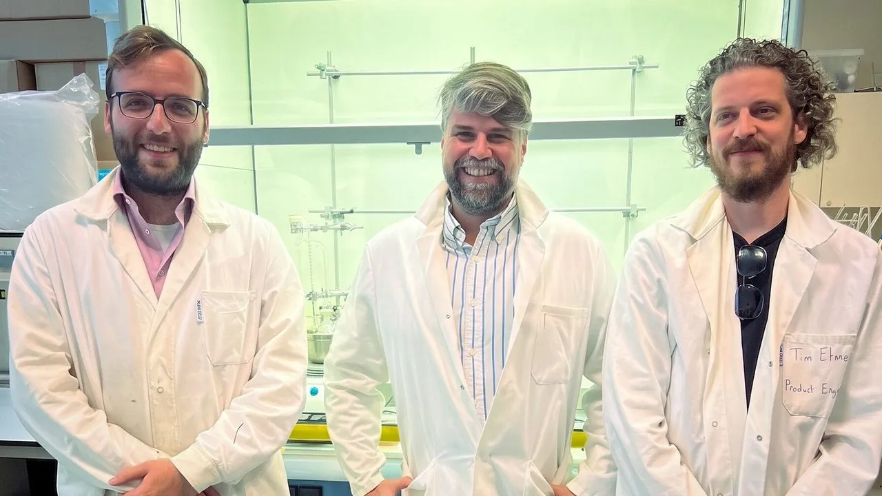 Three men in white lab coats standing in a laboratory.