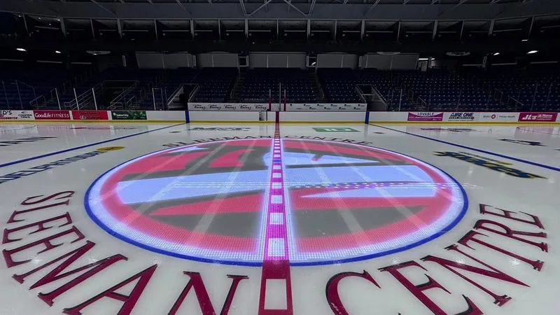 Illuminated center-ice logo and red line at an empty hockey arena.