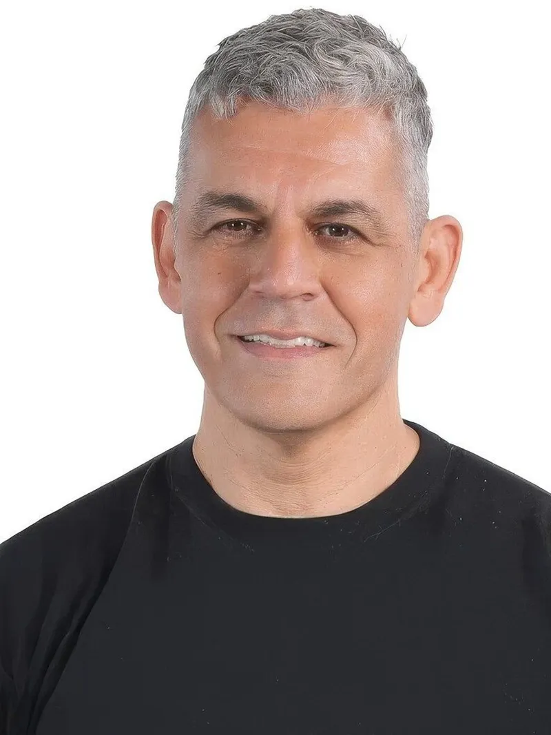 Benny Czarny smiling in a black shirt against a white background.