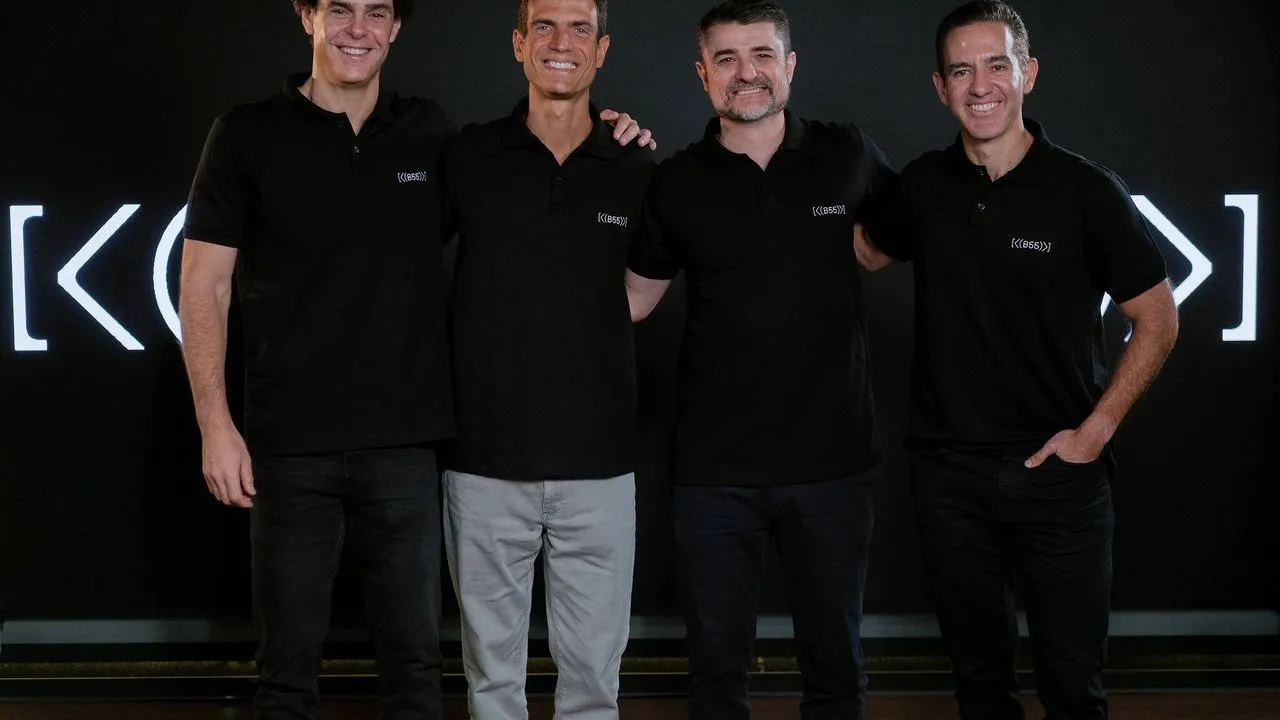Four men in black polo shirts standing together before a black backdrop.