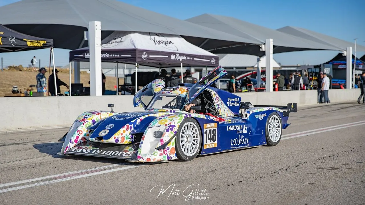 Carbliss and La Macchia Group race car number 148 in a pit lane with its door open.