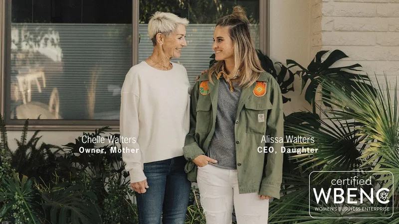 Chelle Walters and Alissa Walters standing together outside among leafy plants.