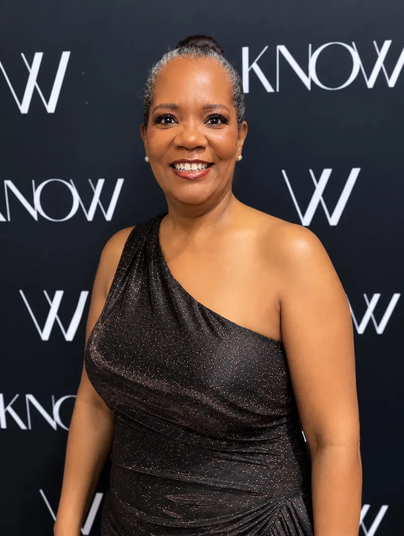 Cheryl McCants in a black one-shoulder dress before a KNOW NJ backdrop.