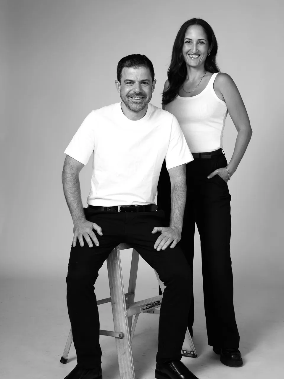 Eyal Firstenberg, left, seated on a step ladder beside Sarah Levy, right, standing.