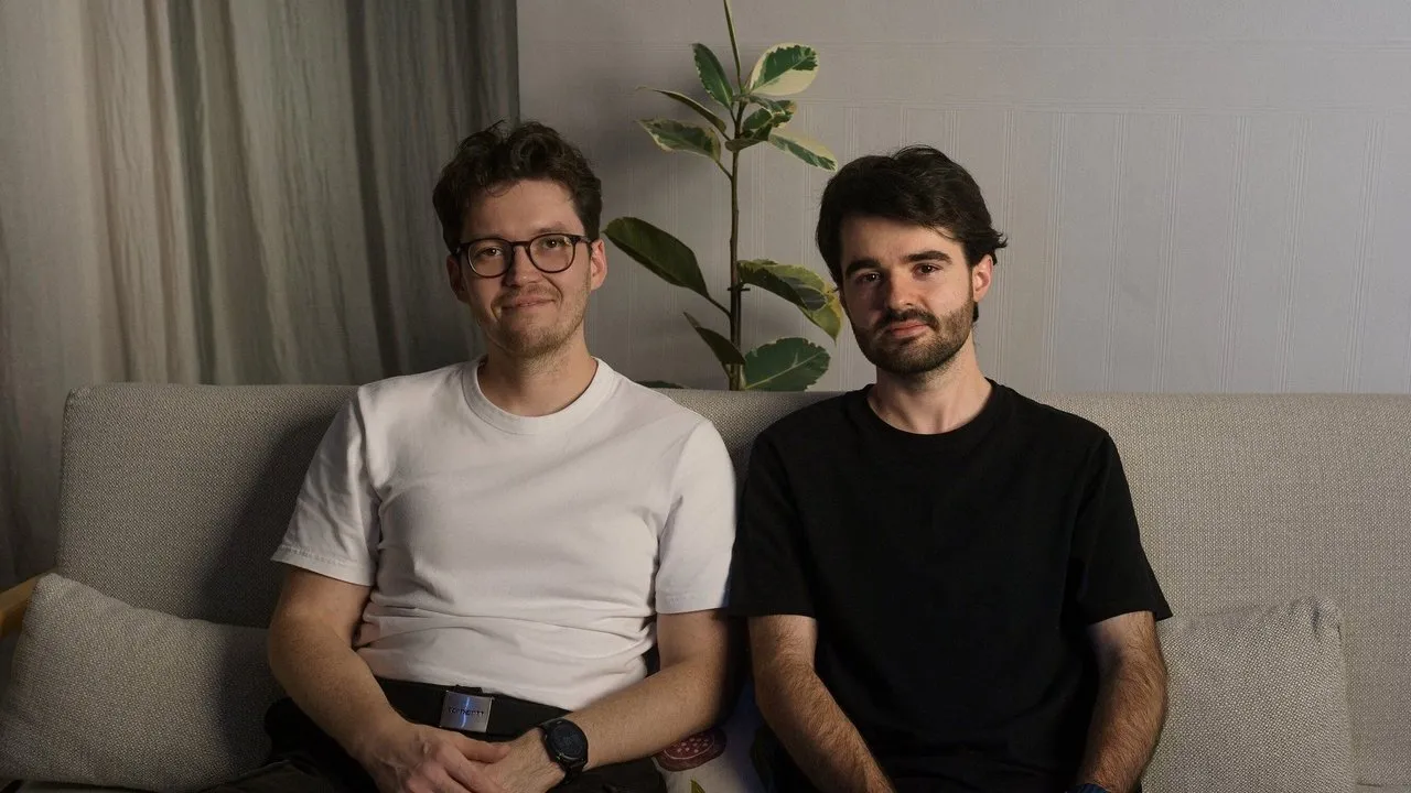 Evgenii Mozharovskii and Maksim Konstantinov seated on a sofa beside a houseplant.