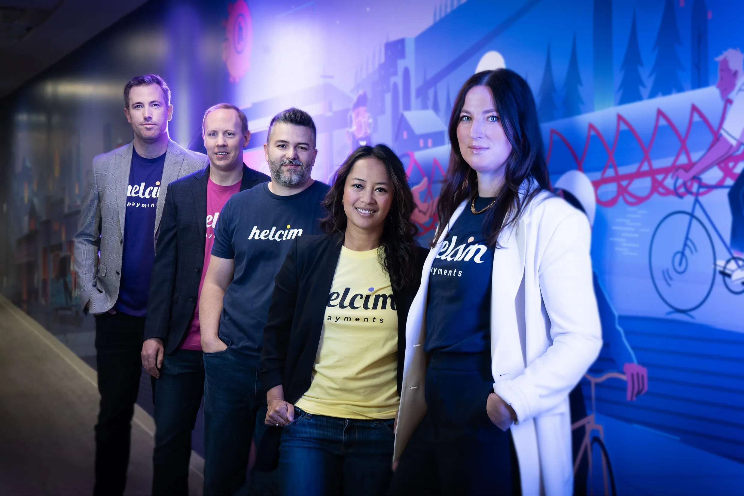 Five Helcim employees standing in front of a colorful mural.