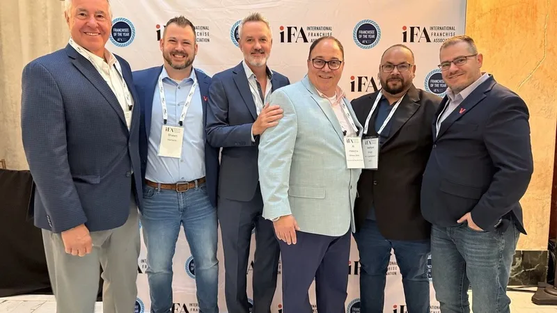 Ieshpal Singh and five Wireless Zone team members at an International Franchise Association event backdrop.