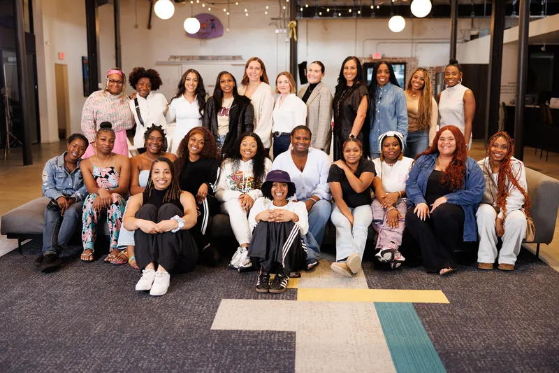 A group of women posing together in an office lounge.
