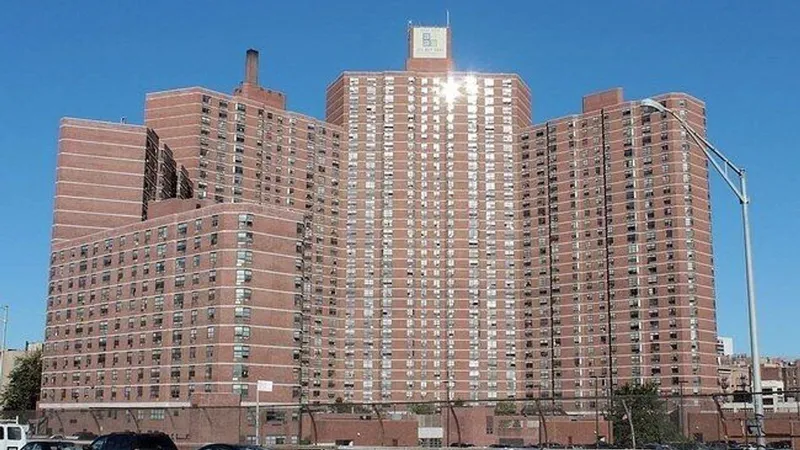 Large brick apartment complex with many windows under a clear blue sky.