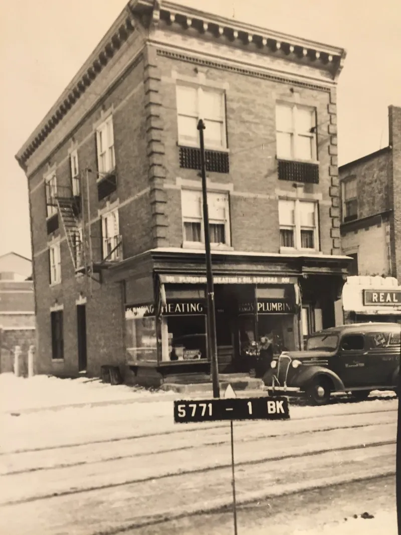 Historic plumbing and heating shop in a brick building, with a vintage delivery truck parked outside.