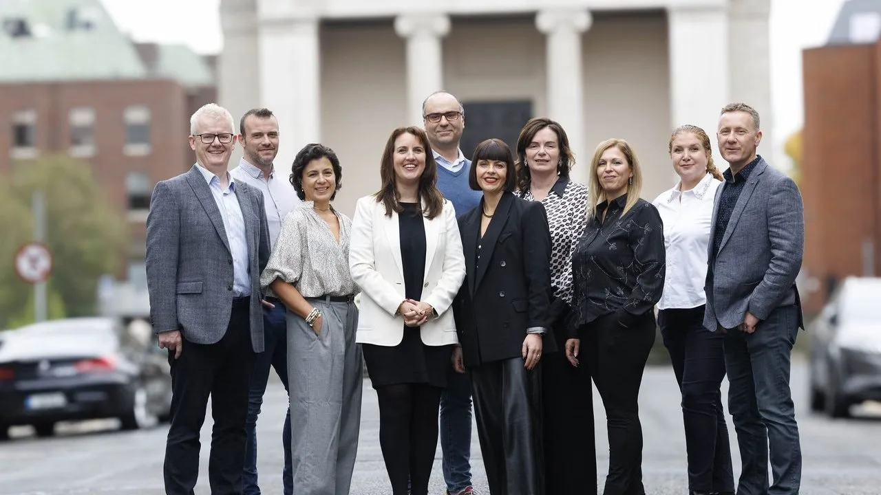 Nine business professionals standing together on a city street.