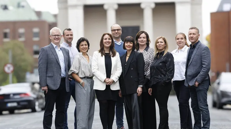 Nine business professionals standing together on a city street.