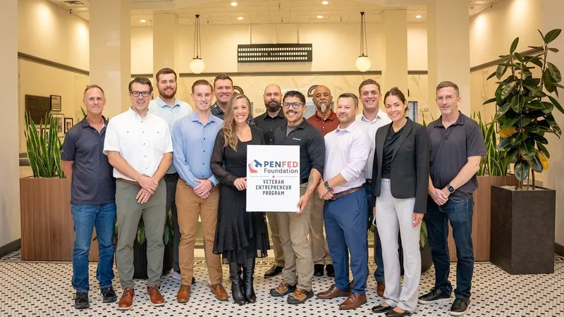 Group of 12 people holding a PenFed Foundation Veteran Entrepreneur Program sign in an office lobby.