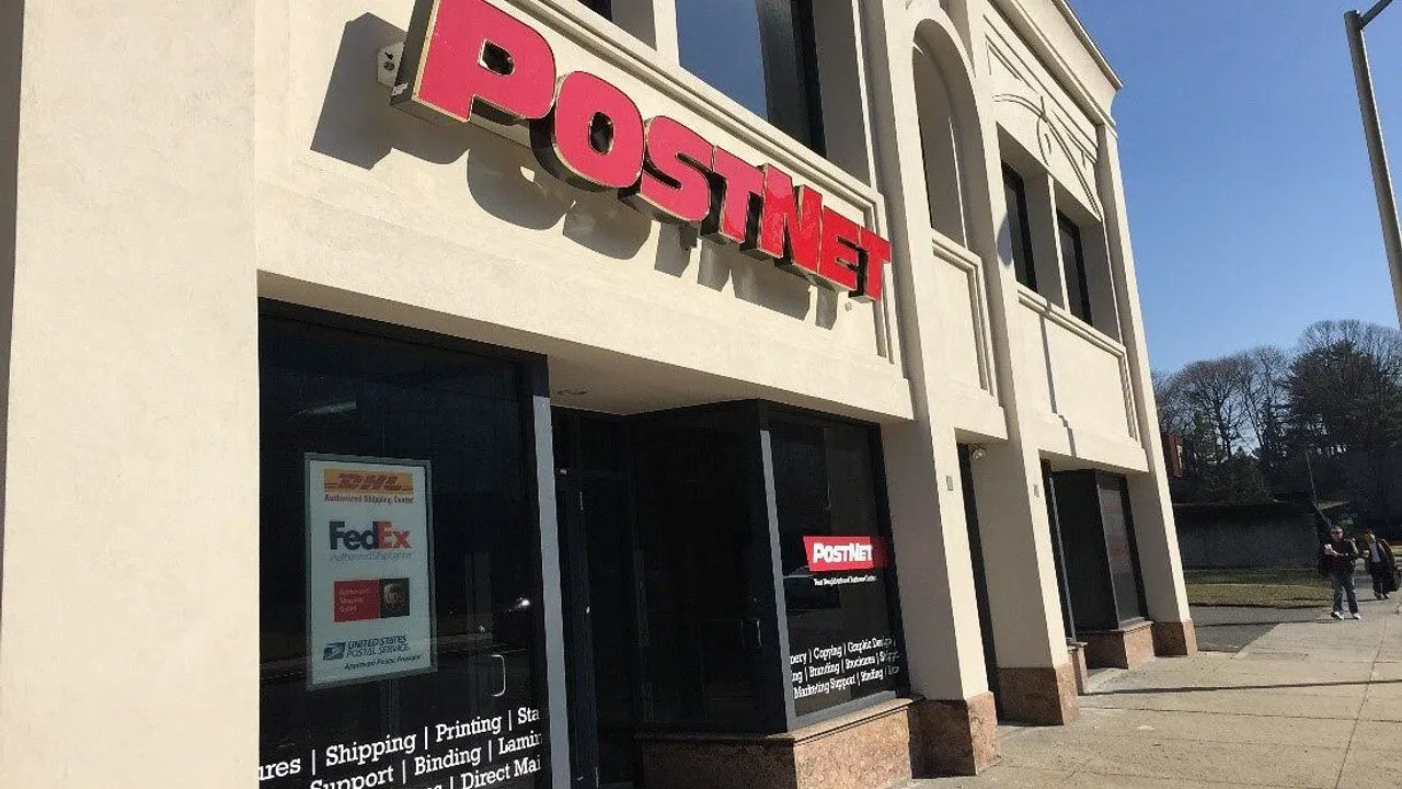 PostNet storefront with red sign and shipping service decals on its windows.