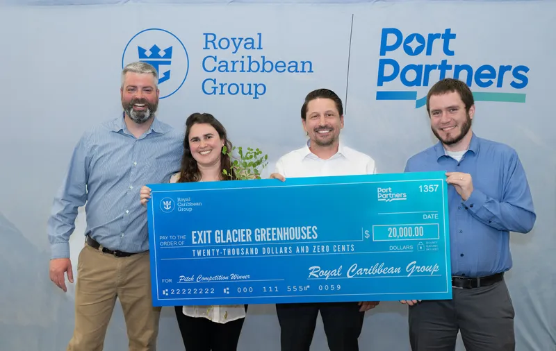 Four people hold a $20,000 check for Exit Glacier Greenhouses before Royal Caribbean Group and Port Partners logos.