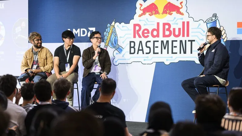 Four men speak onstage at a Red Bull Basement event before an audience.