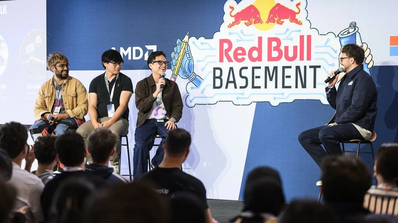 Four men speak onstage at a Red Bull Basement event before an audience.