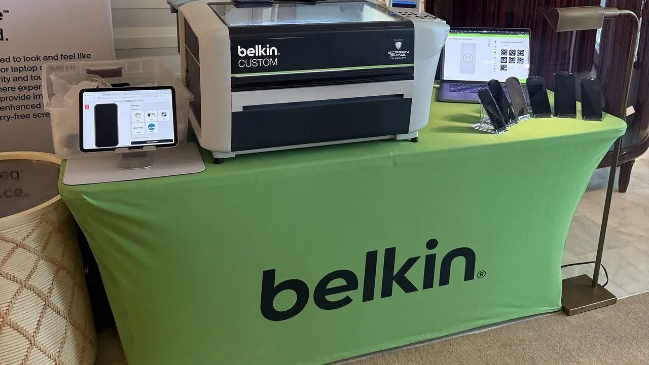 Belkin Custom Screen Skinz printer, tablet, laptop and phones displayed on a green Belkin tablecloth