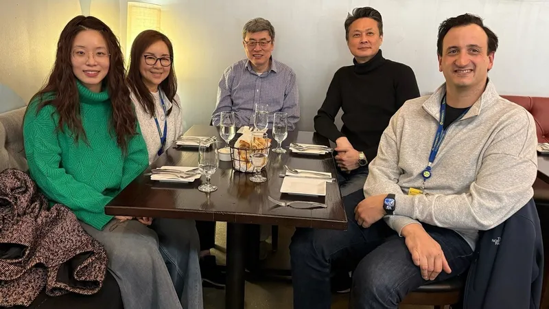 Five people seated around a restaurant table with glasses and bread.