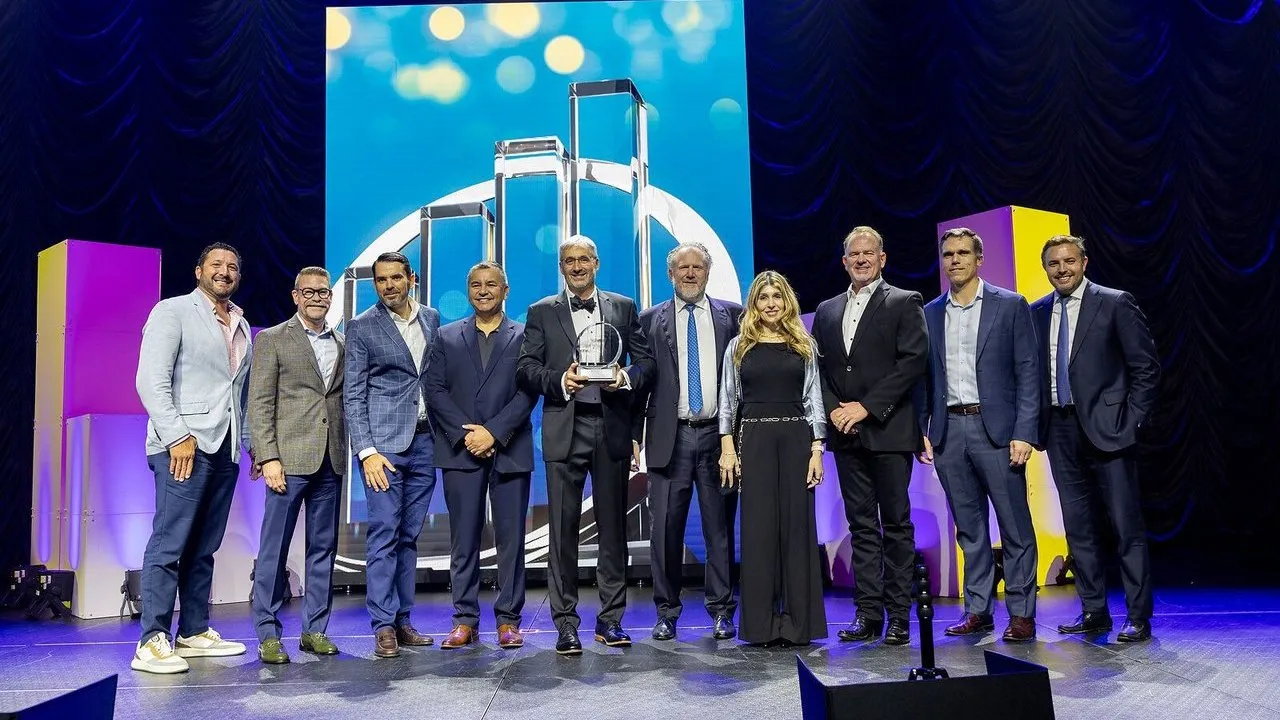 Nine VLS team members stand onstage, with one man holding an EY Entrepreneur Of The Year award.