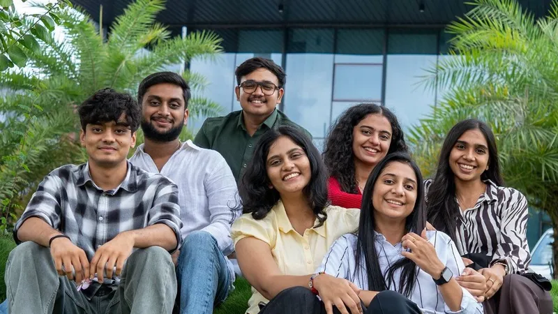 Seven young adults smiling together outdoors amid palm trees.