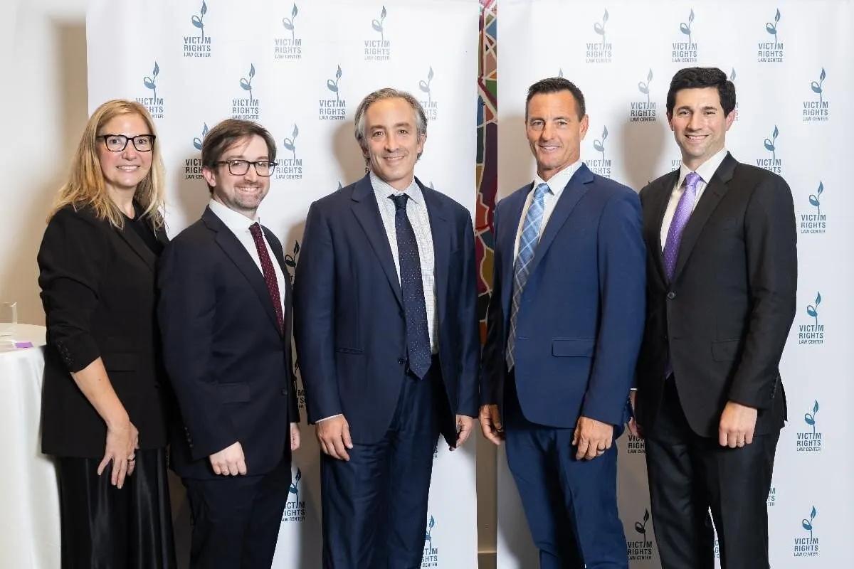 Five people in formal attire pose before a Victim Rights Law Center backdrop.
