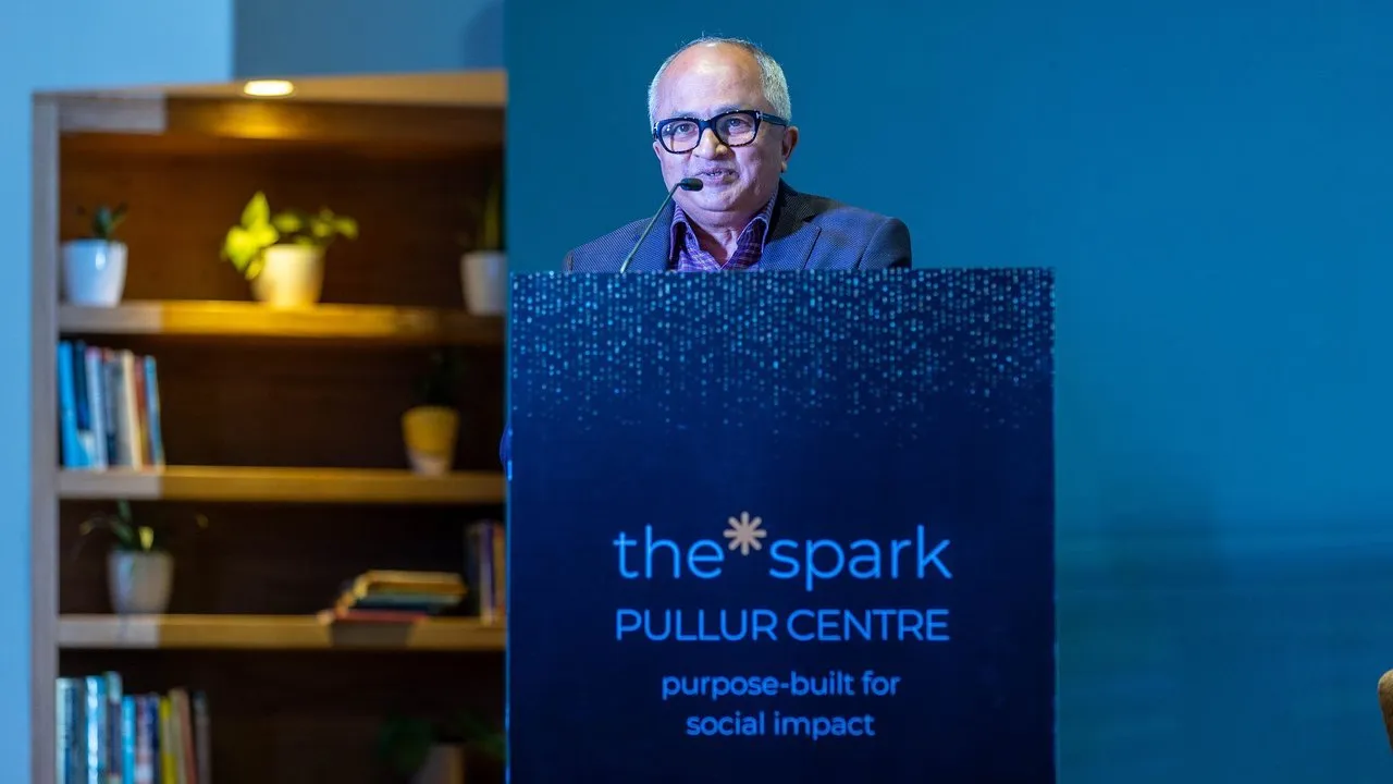 Vijay Pullur speaks at a podium displaying The Spark Pullur Centre logo.