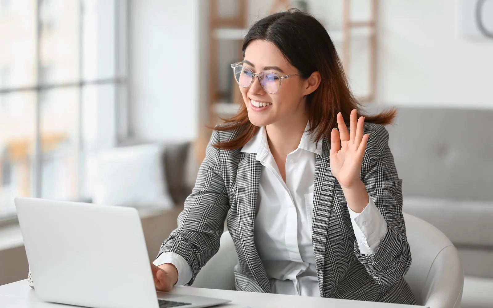 A woman waving to her interviewer on a video call