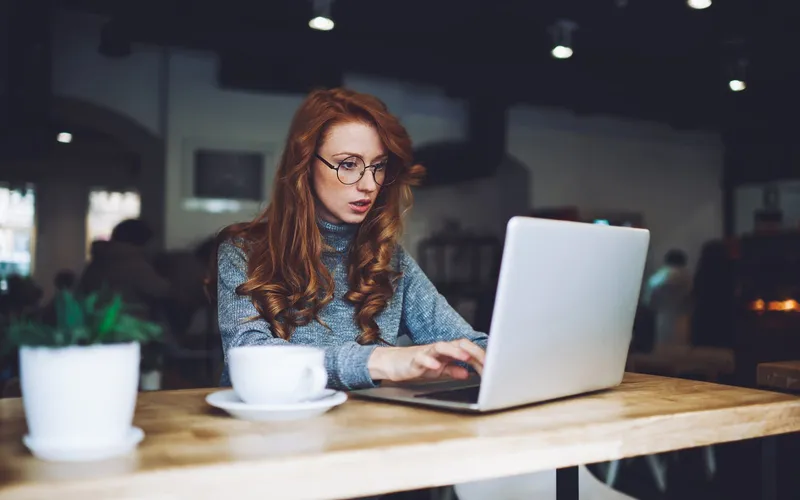A woman working on a laptop in a café