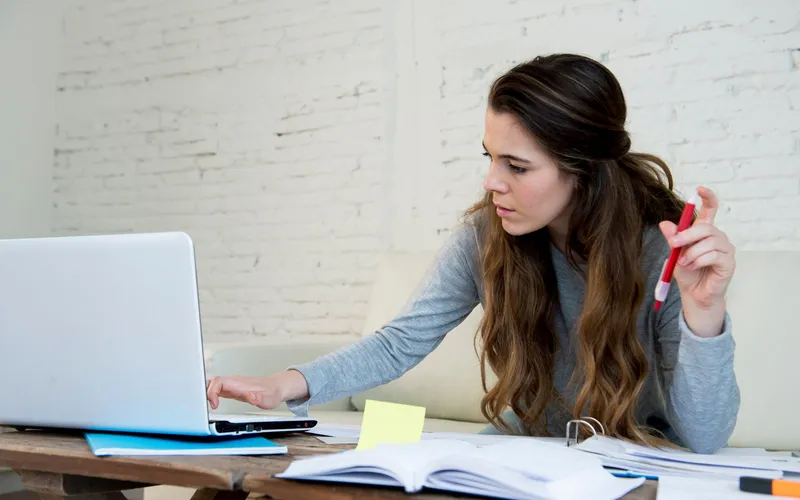 A woman working through paperwork at her laptop