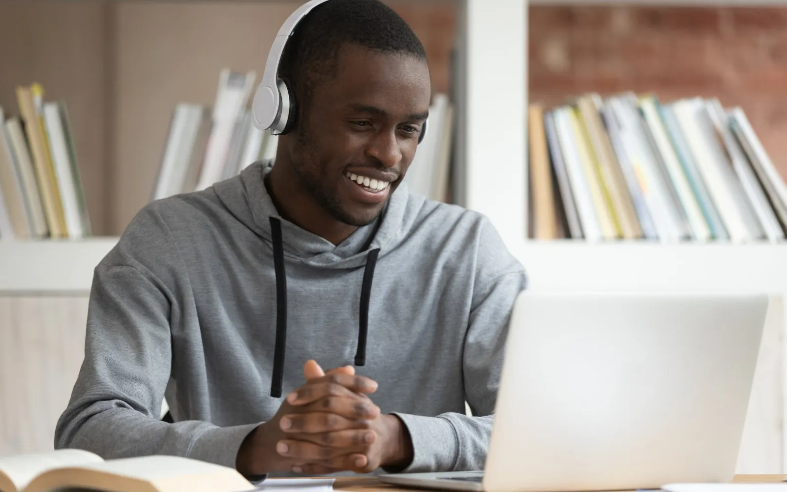 A student with headphones at a laptop in a library