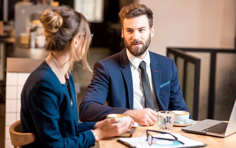 A freelancer talking with a client over coffee in a café