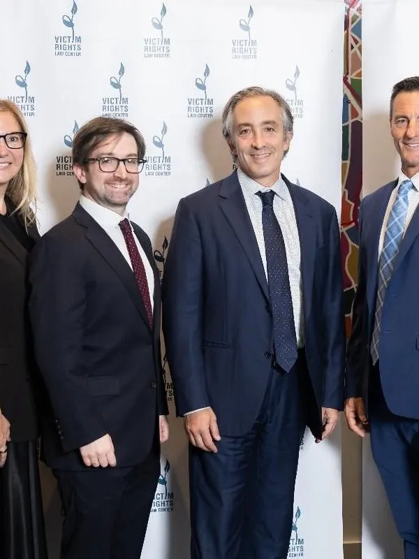 Five people in formal attire pose before a Victim Rights Law Center backdrop.