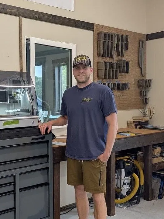 Man standing beside a tool chest with two enclosed machines in a workshop.