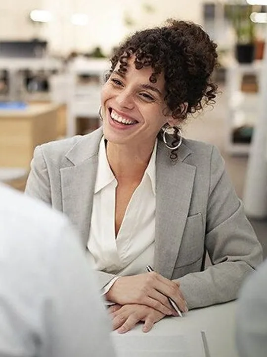 Bank adviser smiling as she speaks with two customers across a desk.