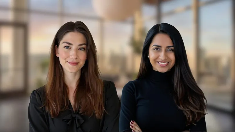 Two women in black tops smiling in an office setting.